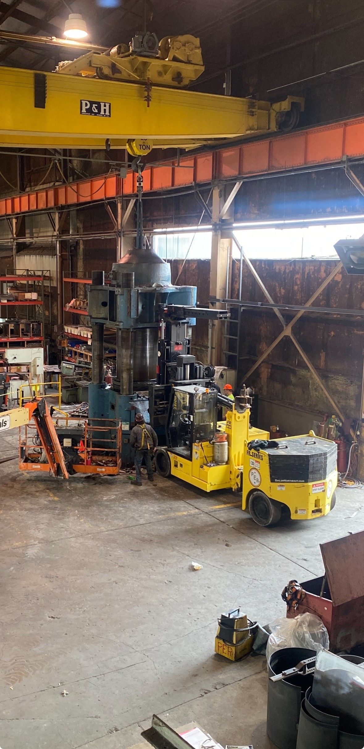 A warehouse filled with lots of machinery and a yellow forklift.