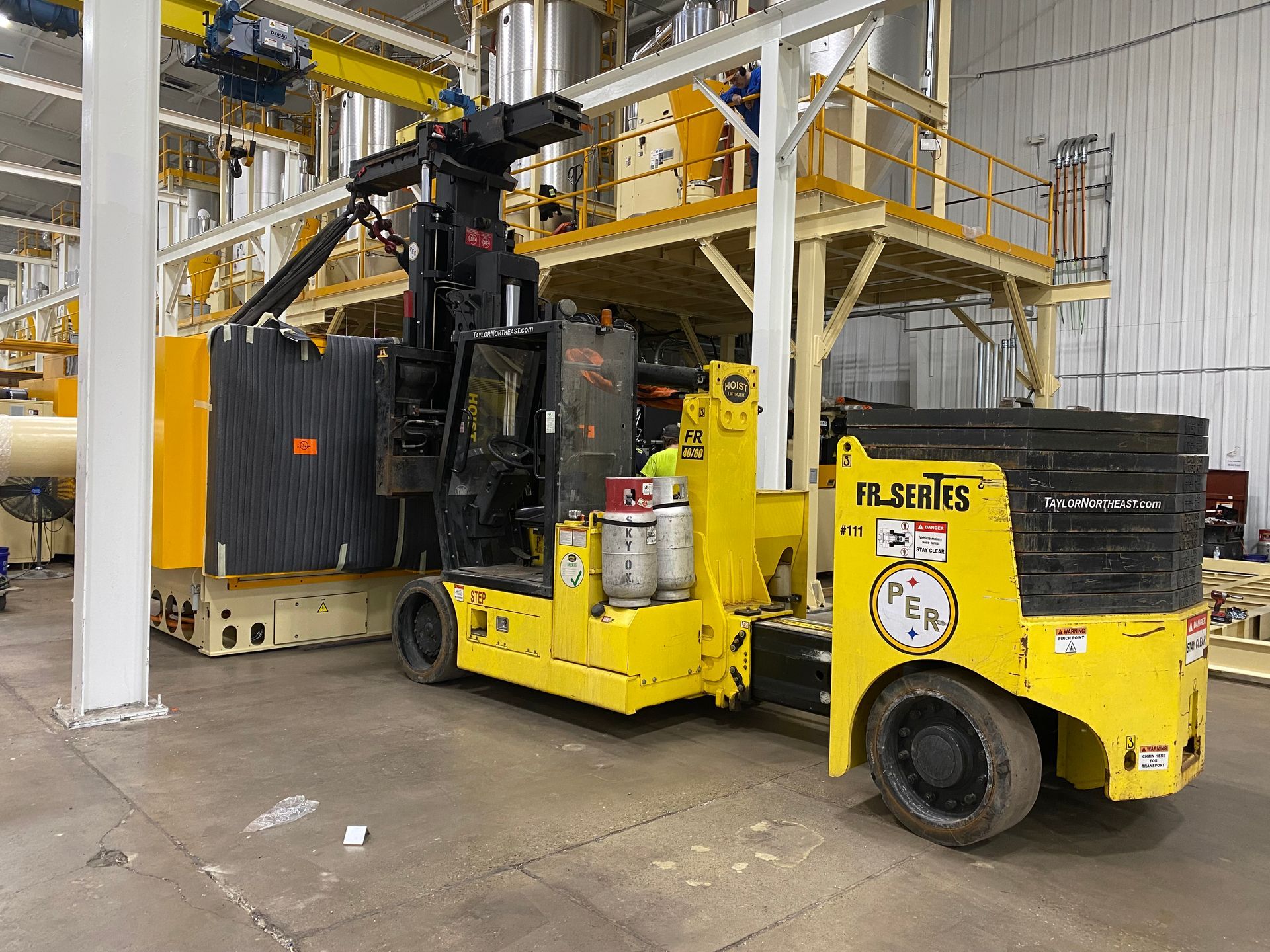 A yellow forklift is parked in a warehouse next to a machine.