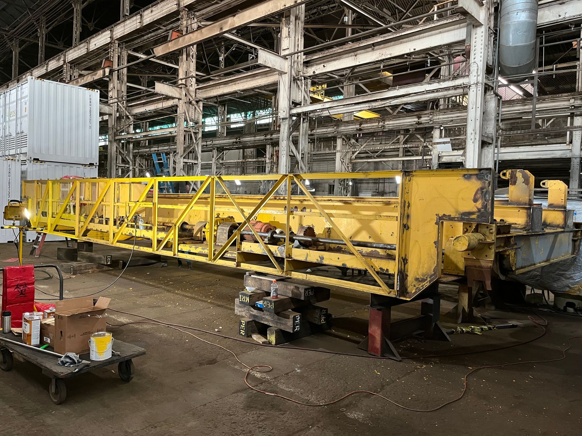 A large yellow crane is sitting in a warehouse.