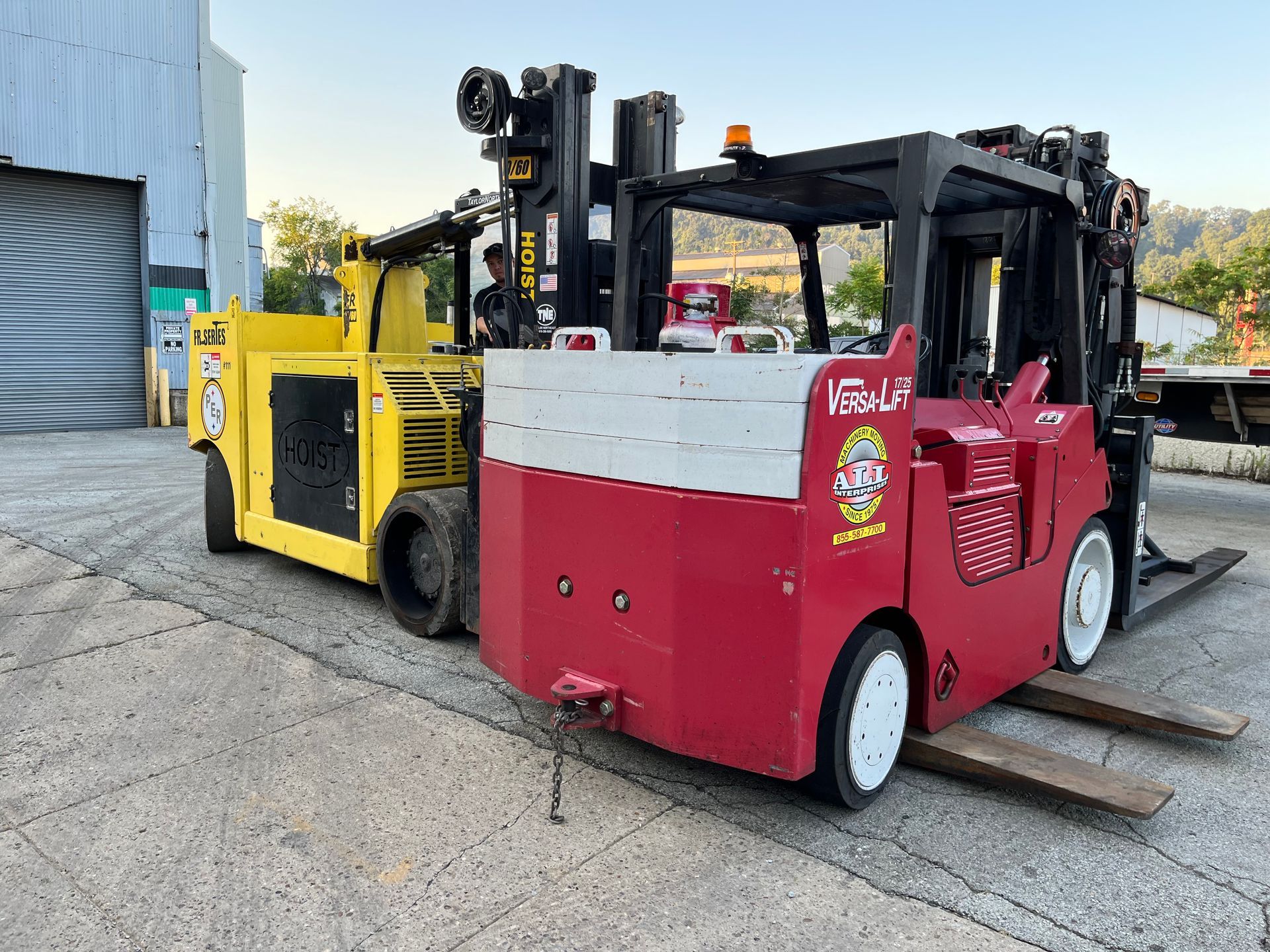 Two forklifts are parked next to each other in a parking lot.