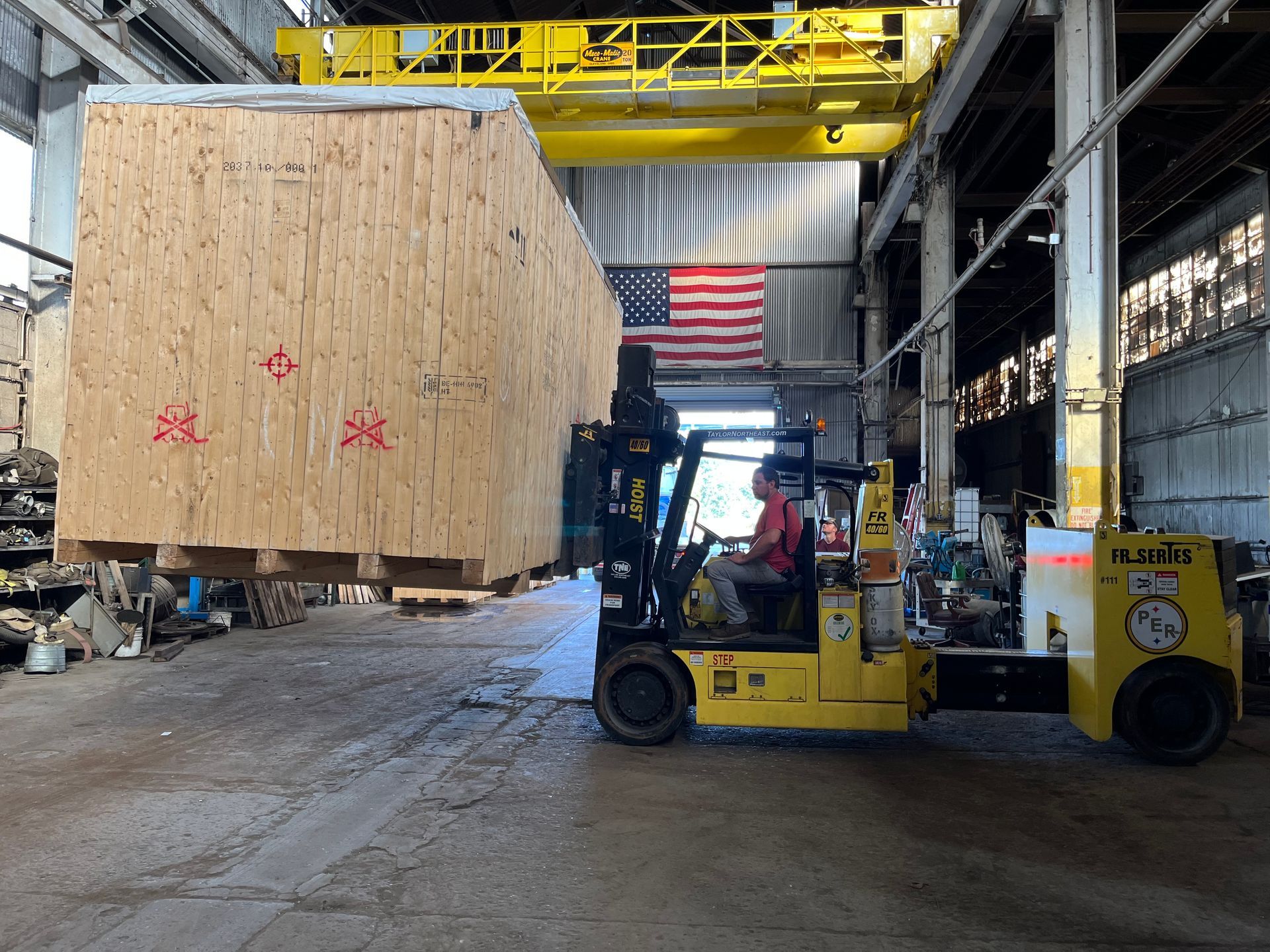 A forklift is lifting a large wooden box in a warehouse