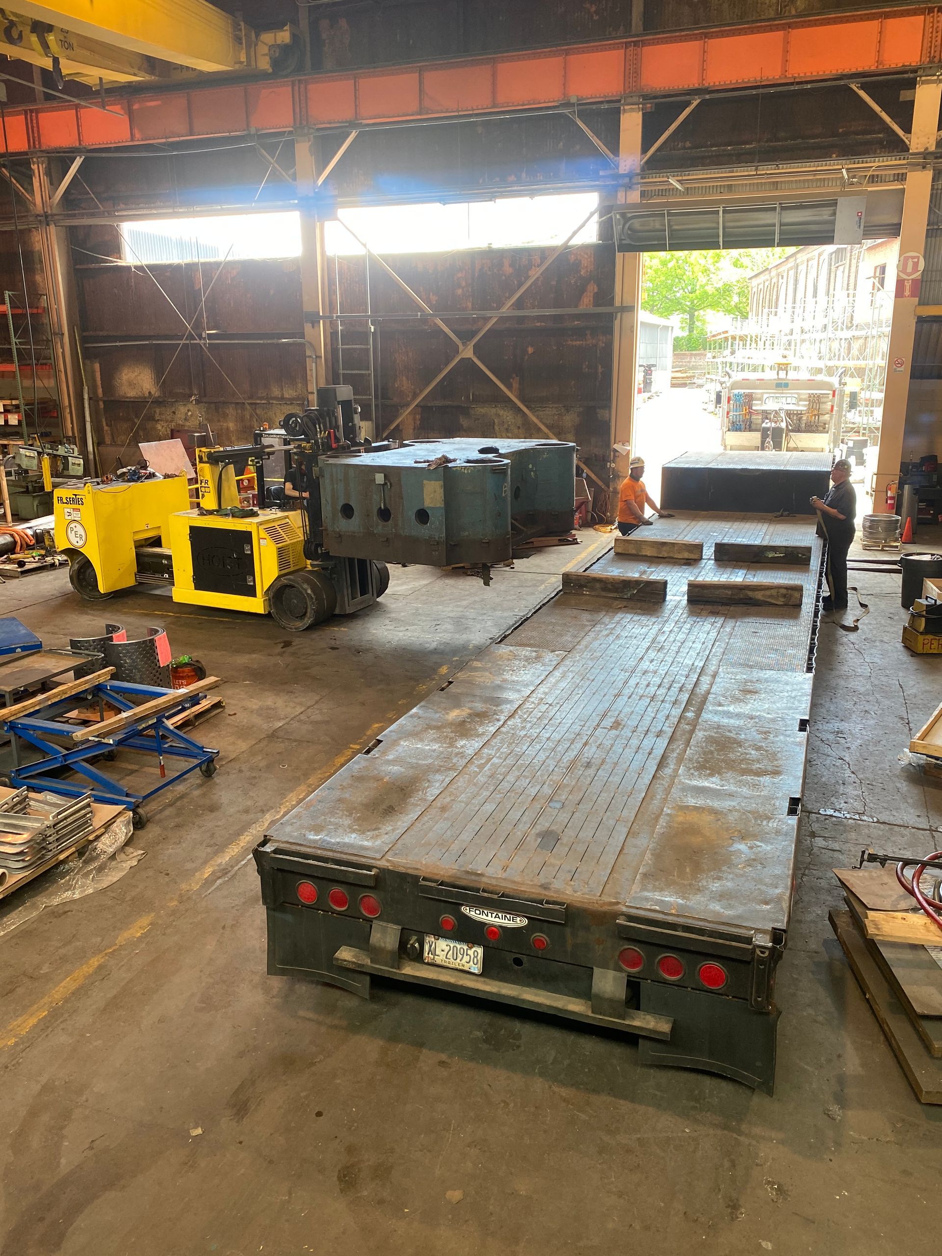 A large trailer is sitting in a warehouse next to a forklift.