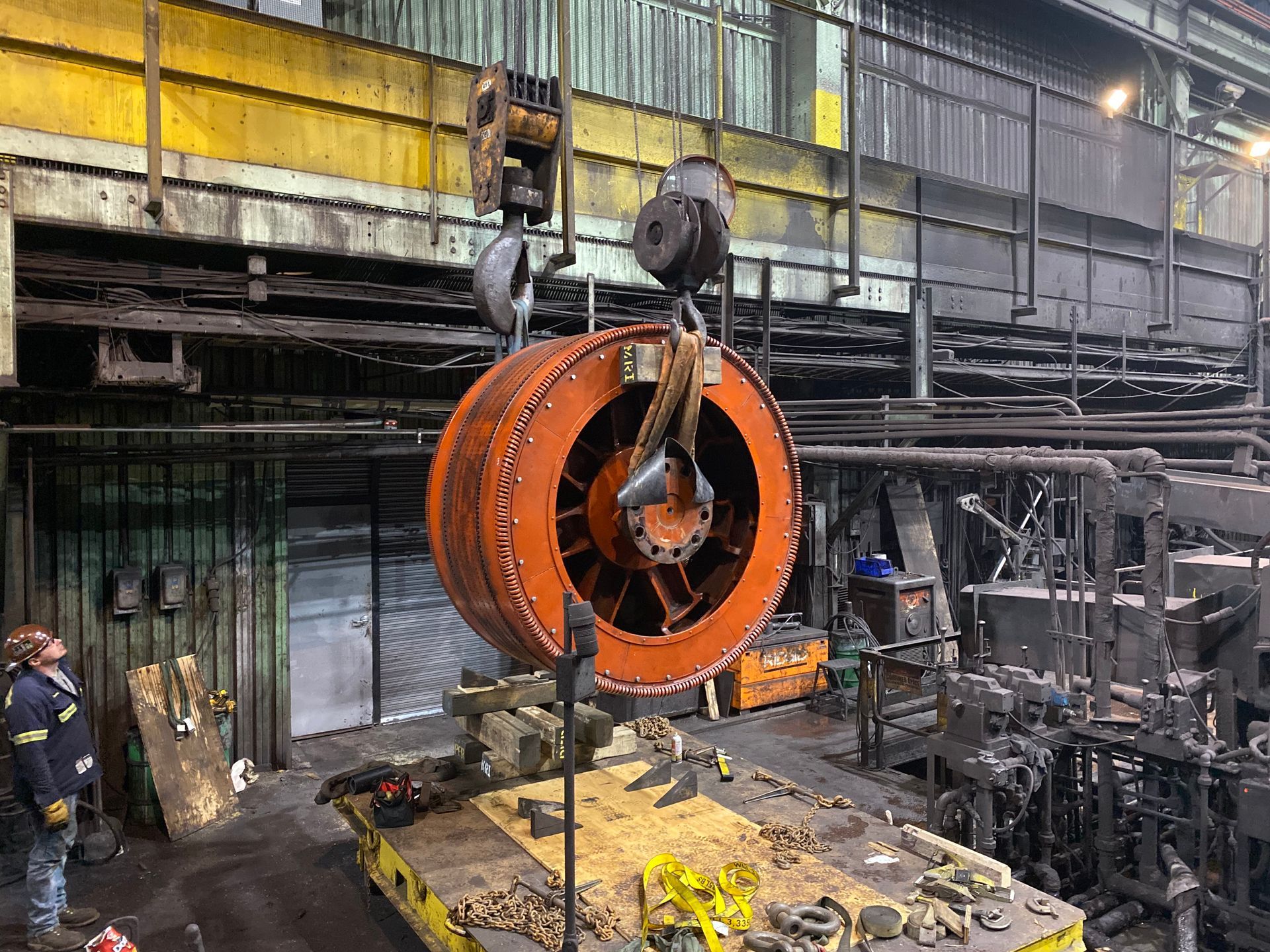 A large fan is being lifted by a crane in a factory.
