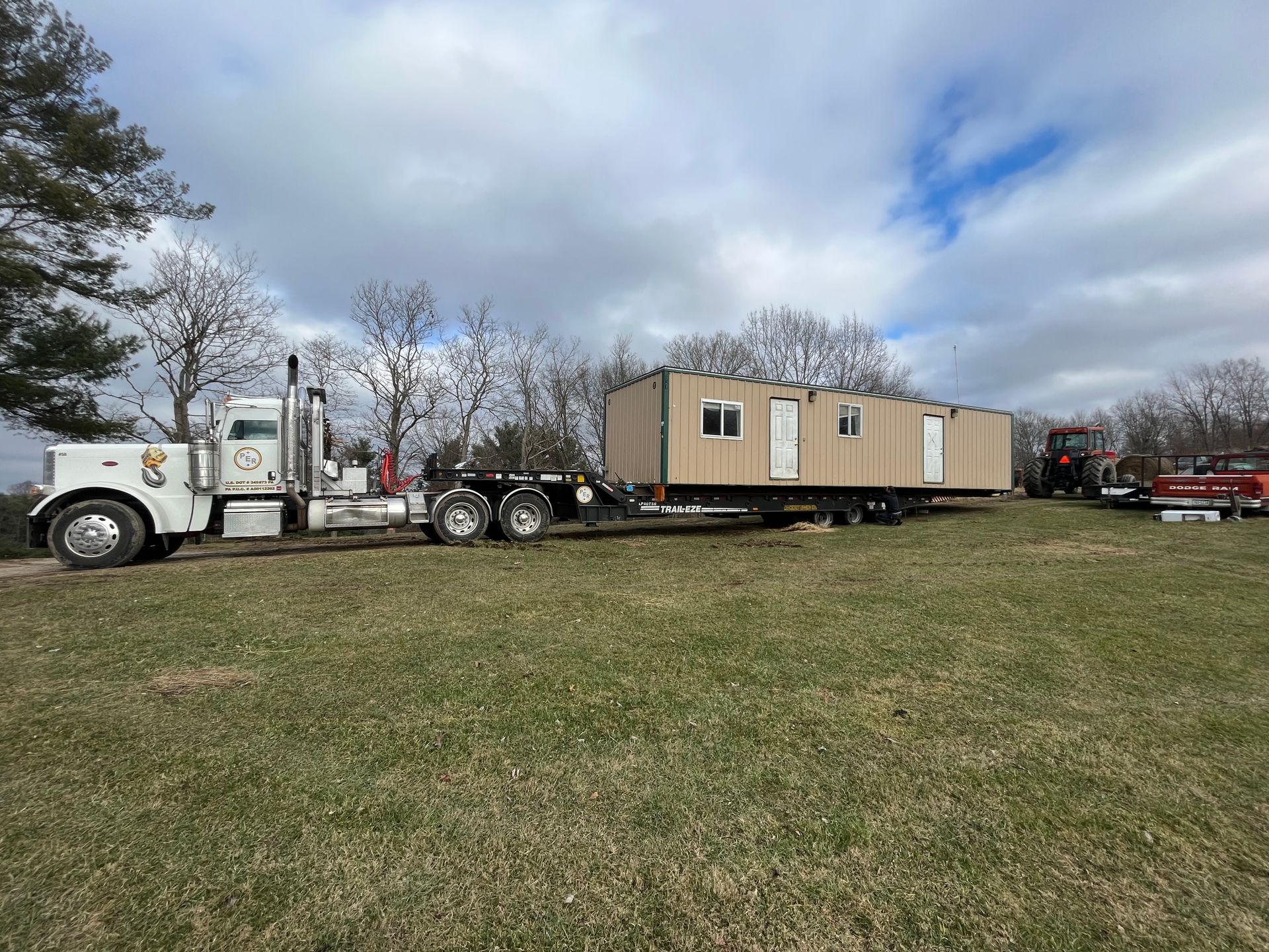 A semi truck is carrying a trailer with a house on it.