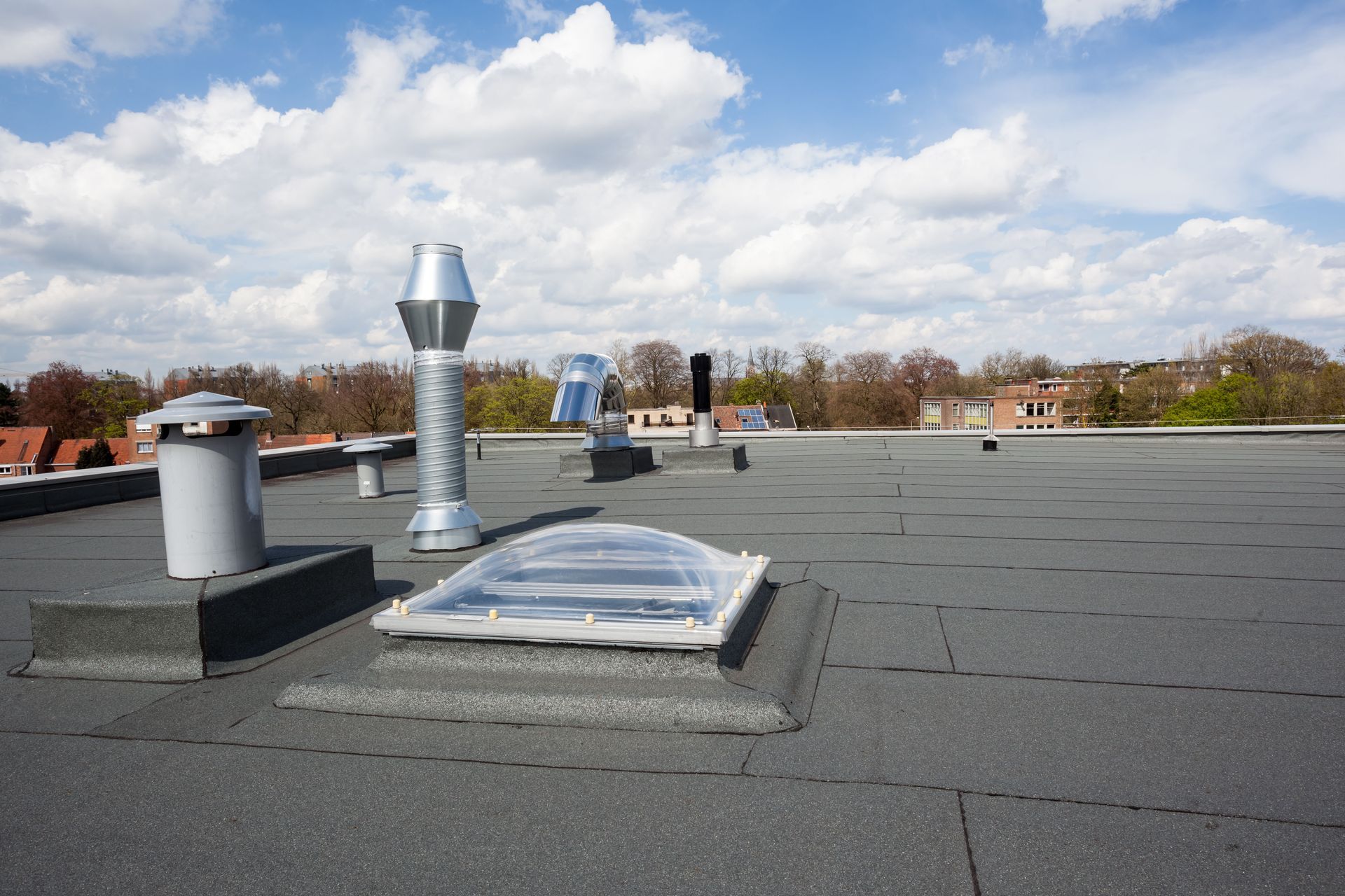 Flat rooftop with vents and a skylight under a cloudy sky