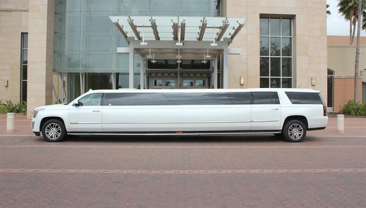 A long white limousine is parked in front of a building
