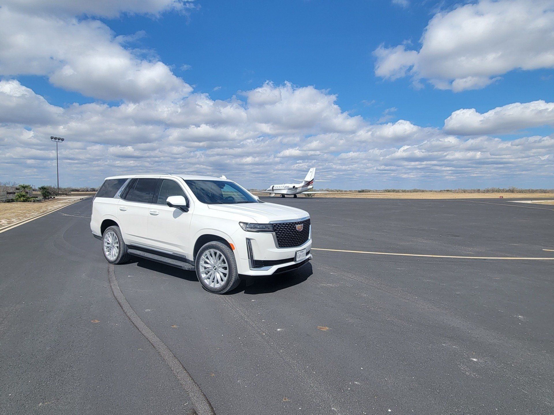 White Escalade and a plane behind it