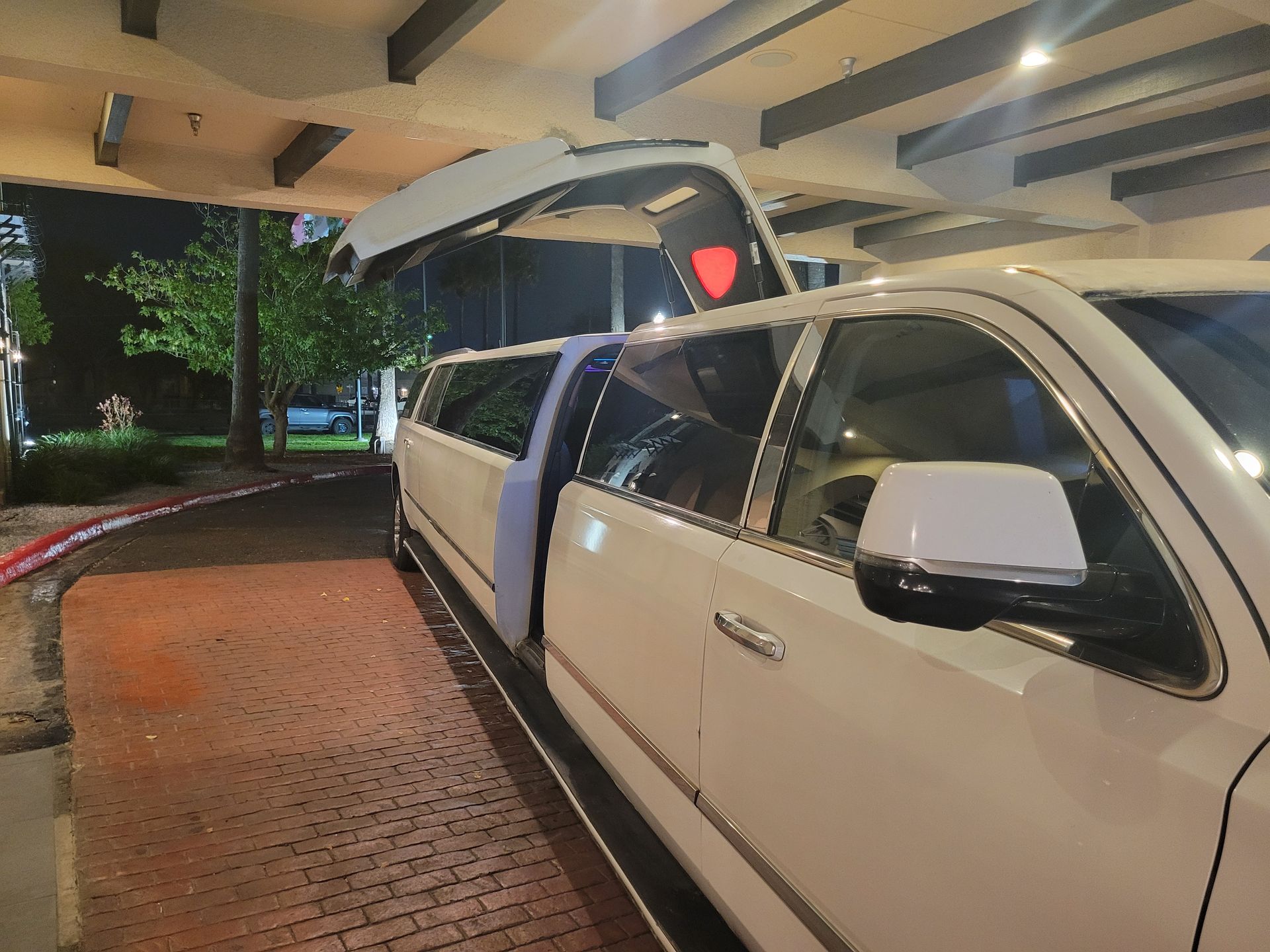 A white limousine with the trunk open is parked in a parking lot.
