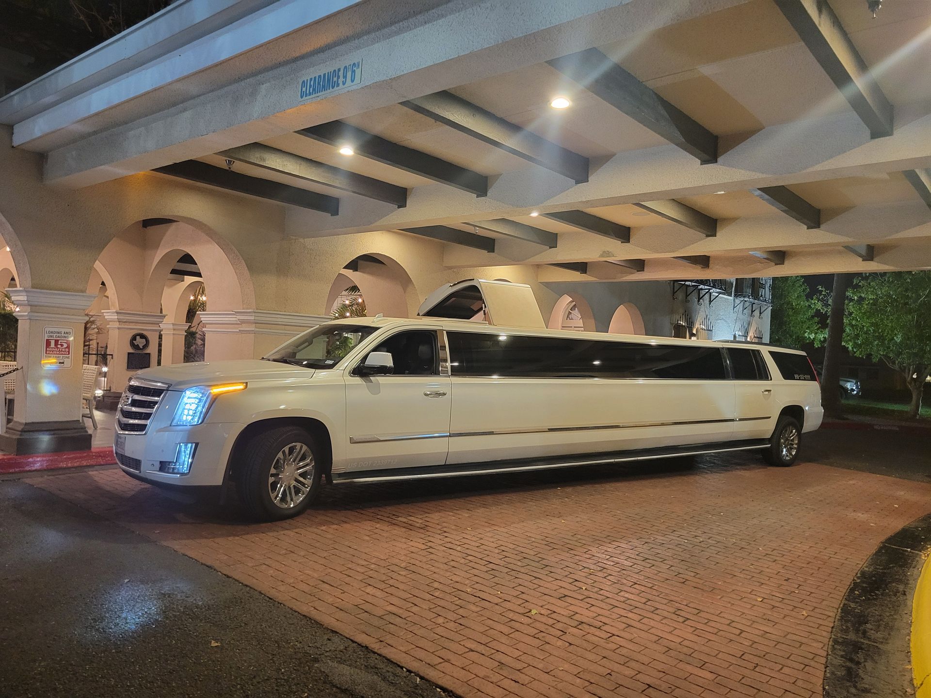 A white limousine is parked under a building at night.