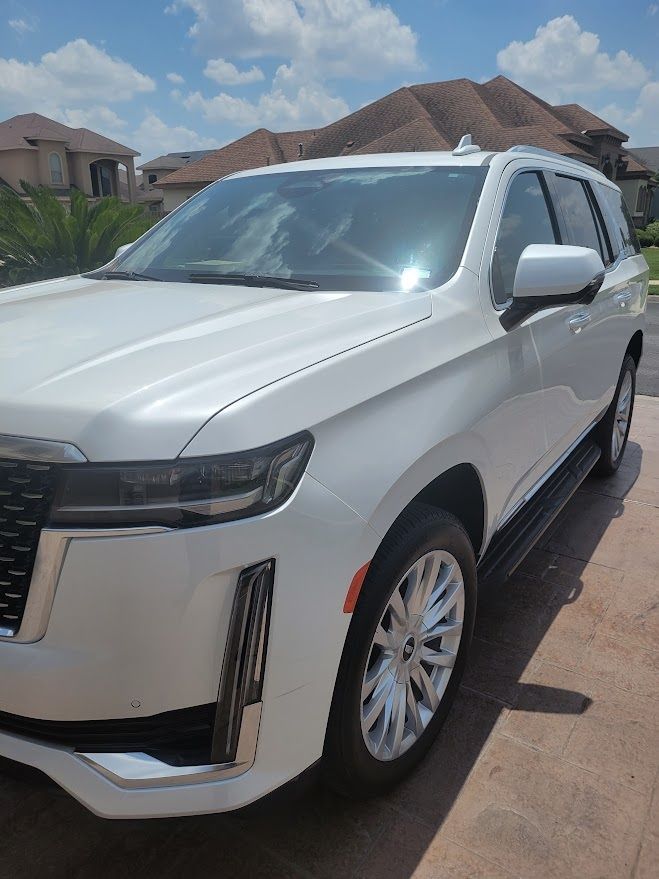 A white suv is parked in a driveway on a sunny day