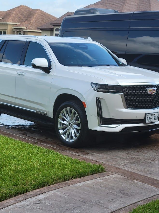 A white suv is parked in a driveway next to a black van.