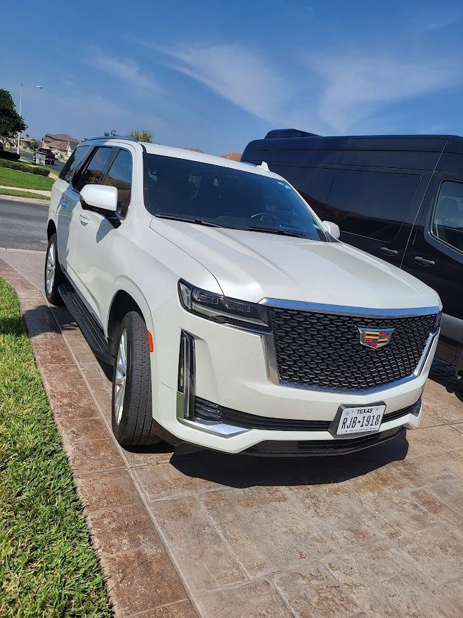 A white Cadillac Escalade is parked on the side of the road.