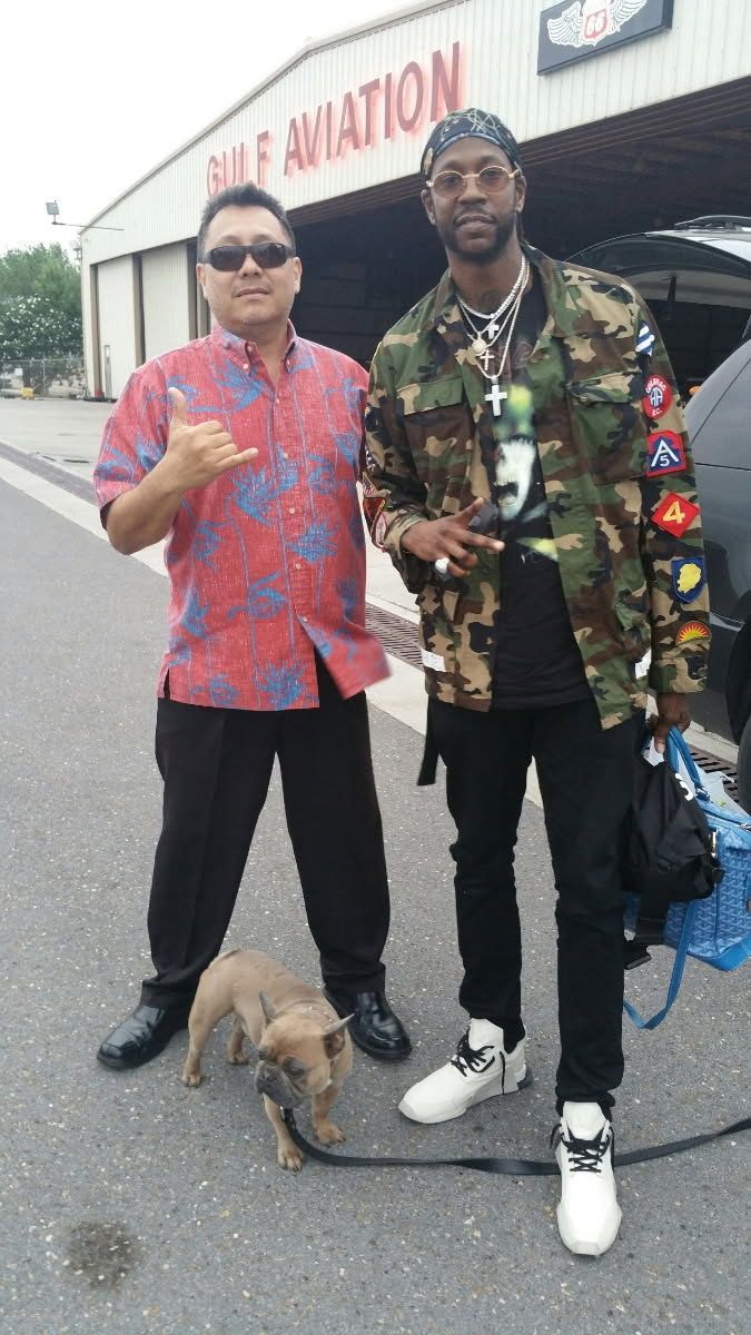 Two people stand outside Gulf Aviation one wearing a red patterned shirt, the other in camouflage, with a small dog.