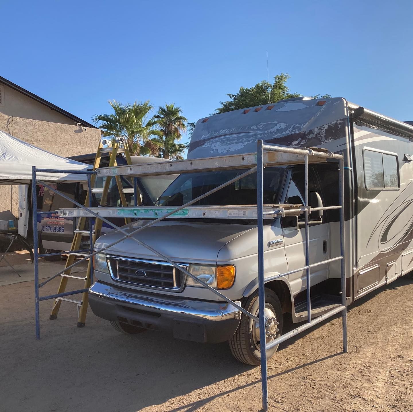Several recreational vehicles parked on a grassy field under a vibrant orange and purple sunset sky.