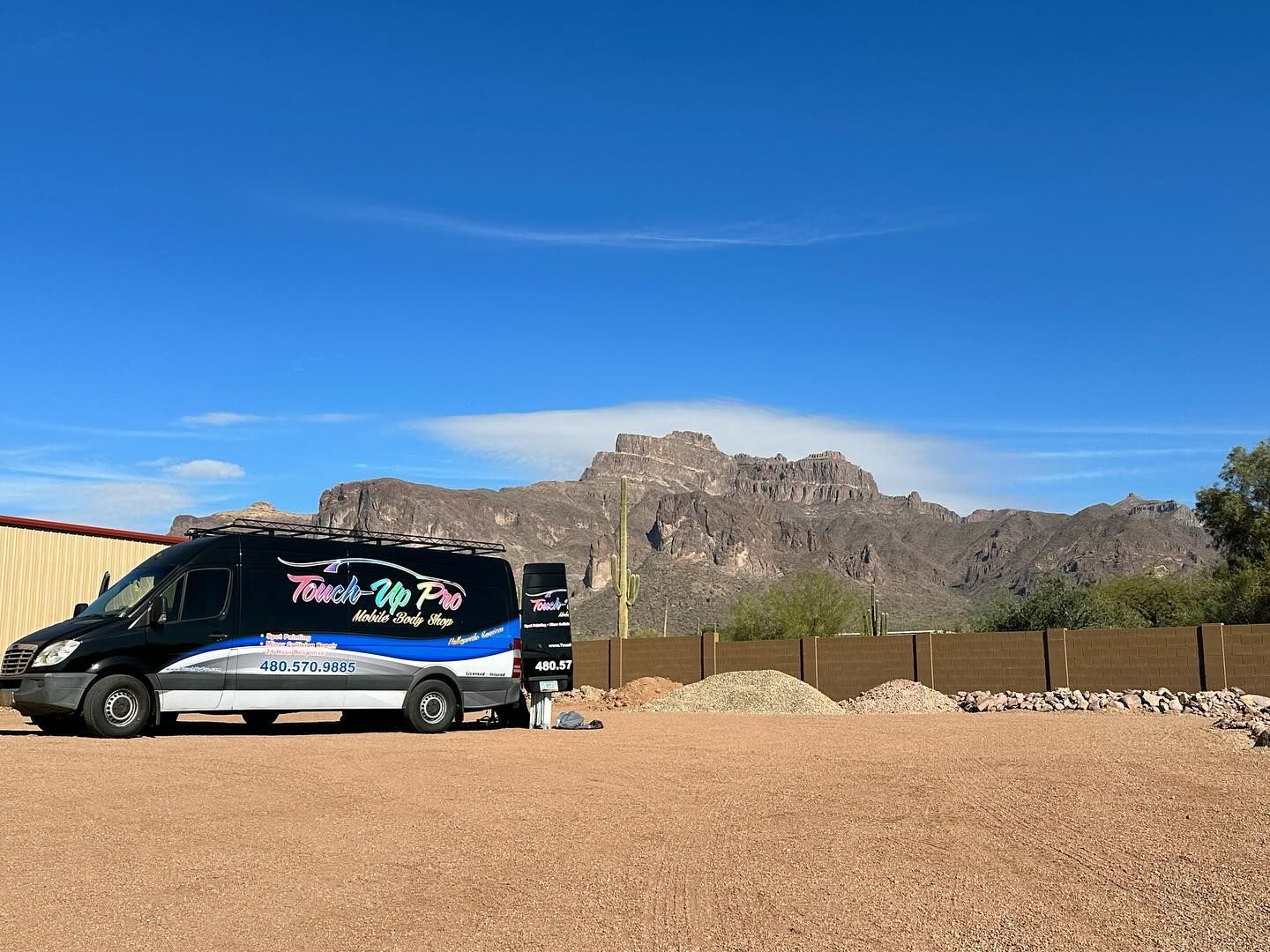 A white Volvo C30 parked on a dark paved road during a vibrant sunset with rolling hills in the background.