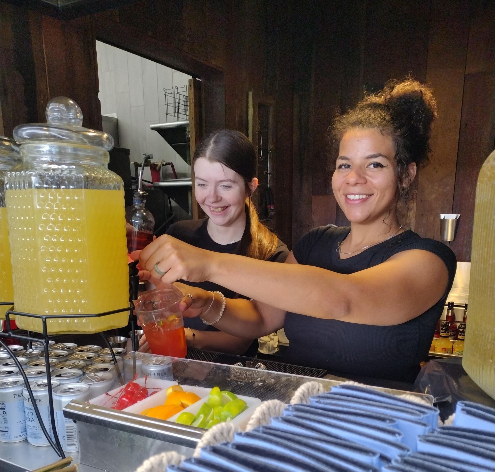 Two women are standing behind a counter with bottles of water and flowers.