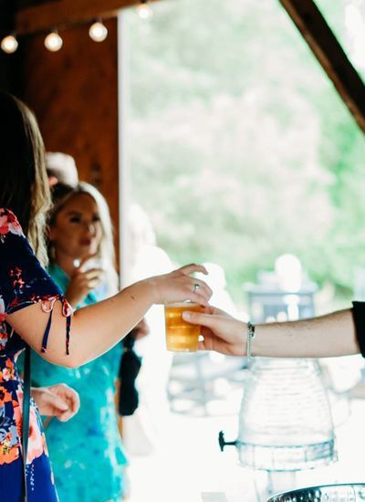 A woman is giving a glass of beer to another woman.