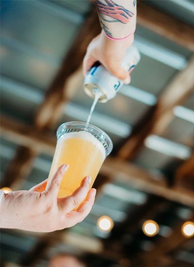 A person is pouring beer into a plastic cup.