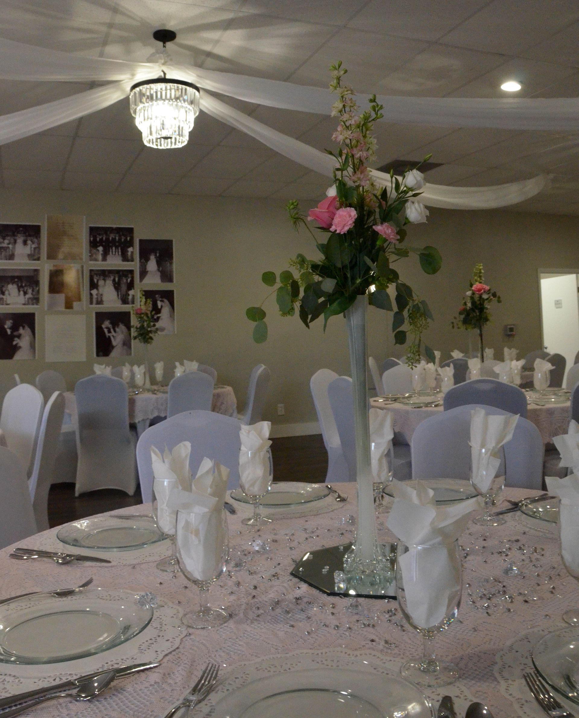 A table set for a wedding reception with a vase of flowers on it