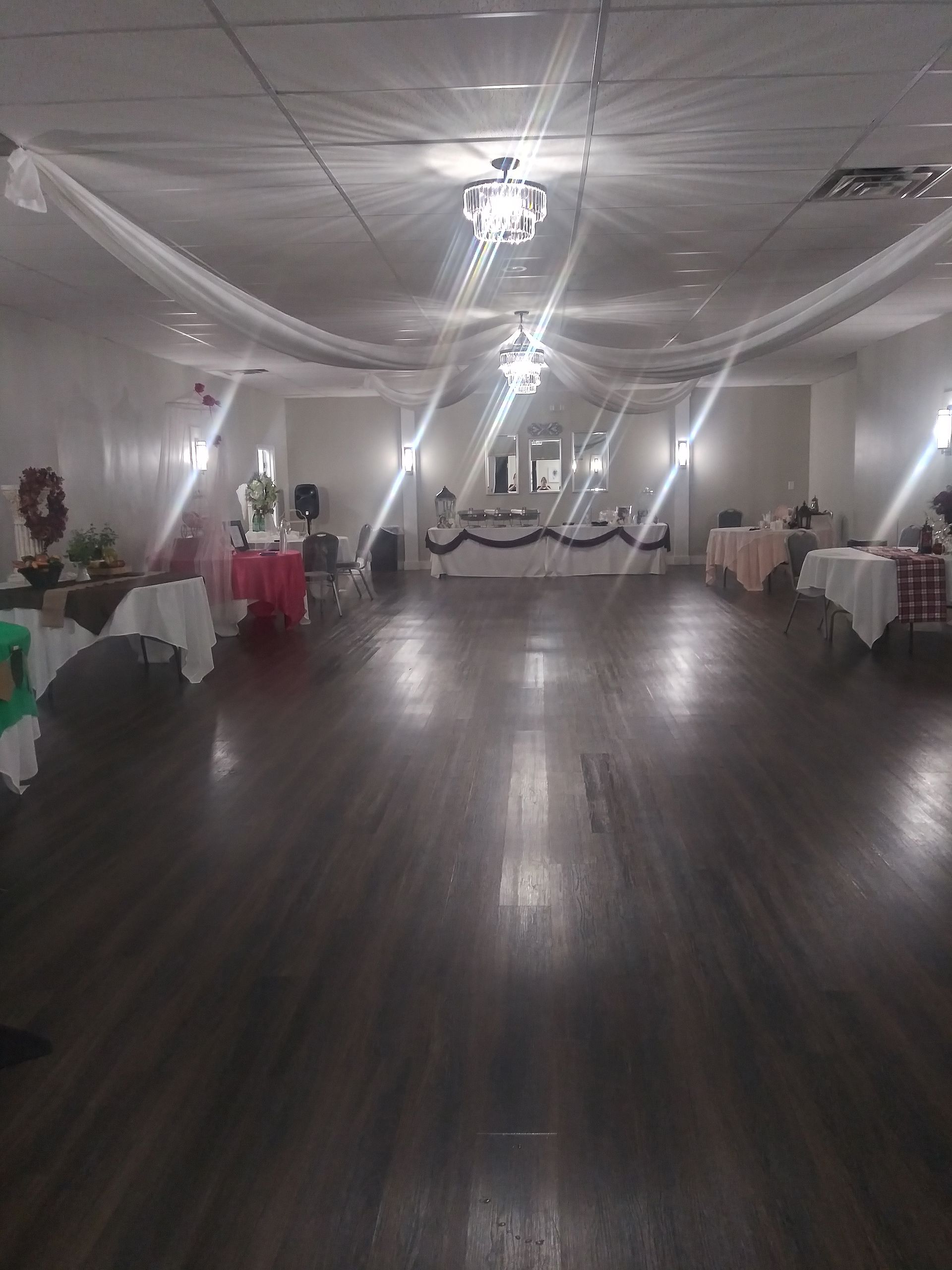 A large room with tables and chairs set up for a wedding reception.