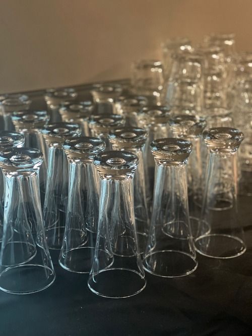A bunch of empty glasses are lined up on a table.