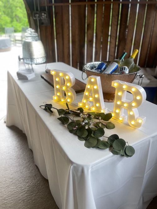 A table with a white tablecloth and a bar sign on it.