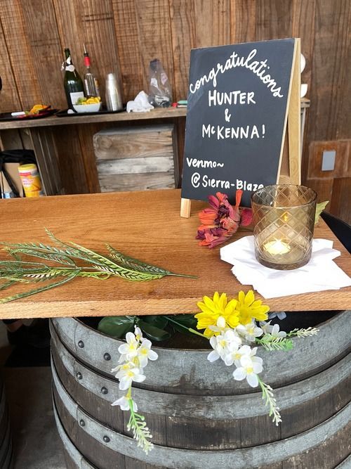 A wooden table with flowers and a sign that says `` congratulations hunter & mckenna ''.