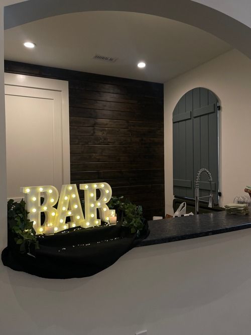 A lighted bar sign is sitting on a counter in a kitchen.