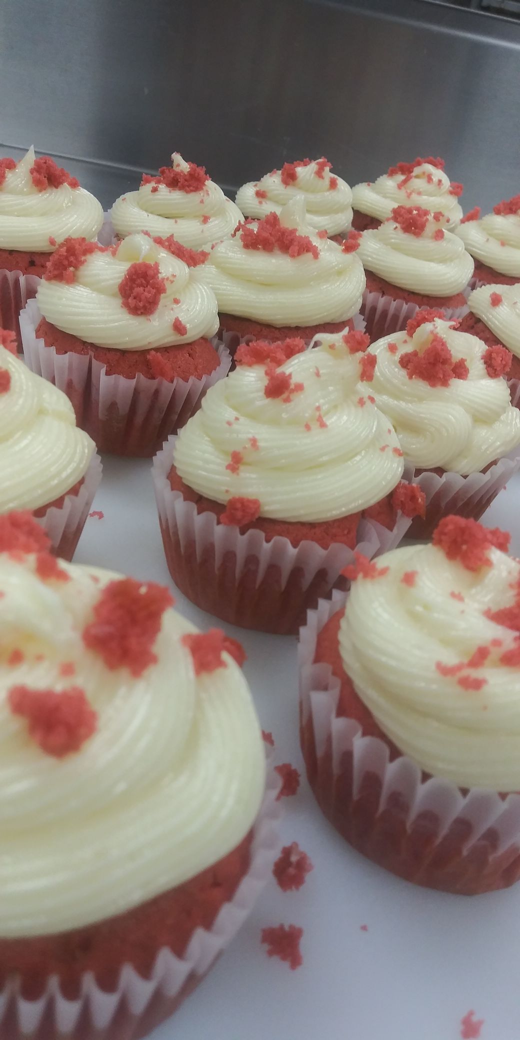 A bunch of red velvet cupcakes with white frosting
