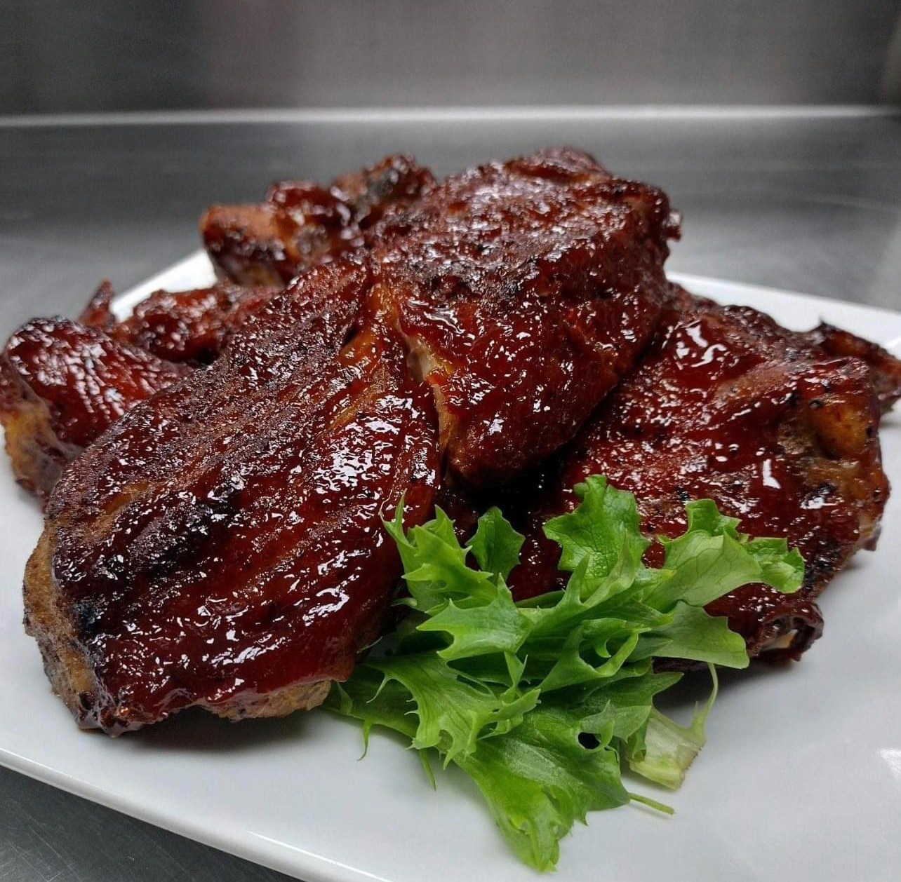 A white plate topped with barbecue ribs and lettuce