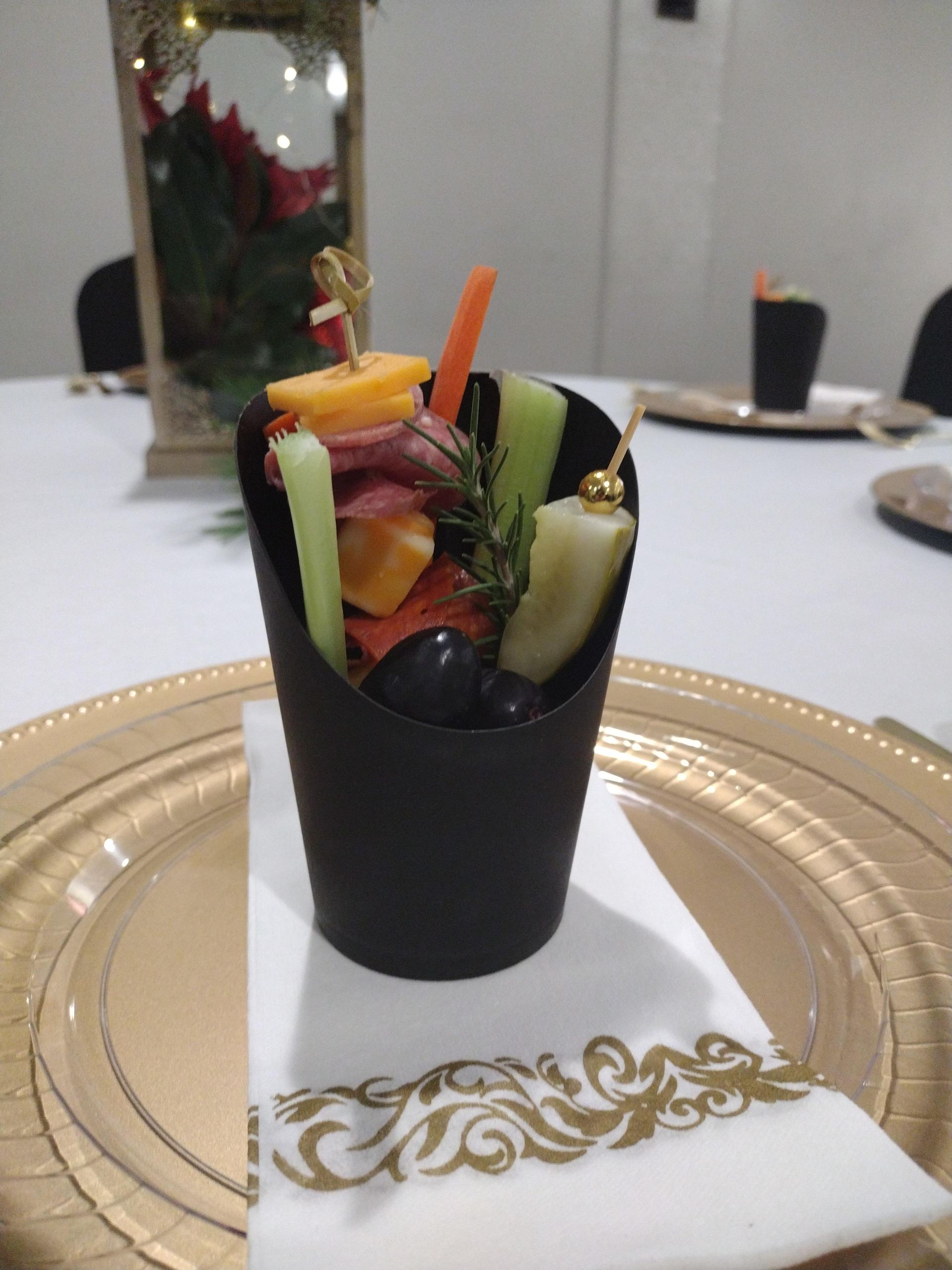 A black cup filled with fruit and vegetables on a napkin on a plate