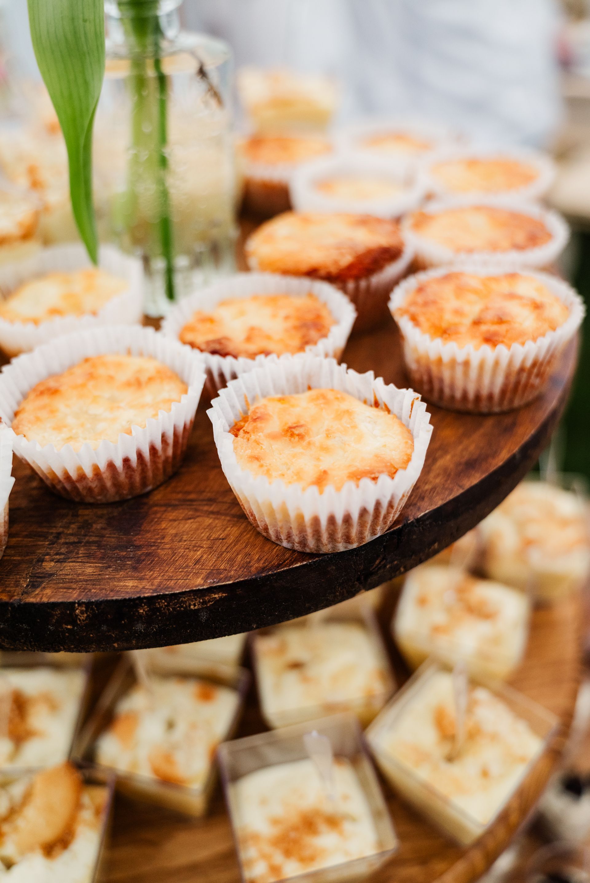 A wooden tray filled with cupcakes and other desserts.