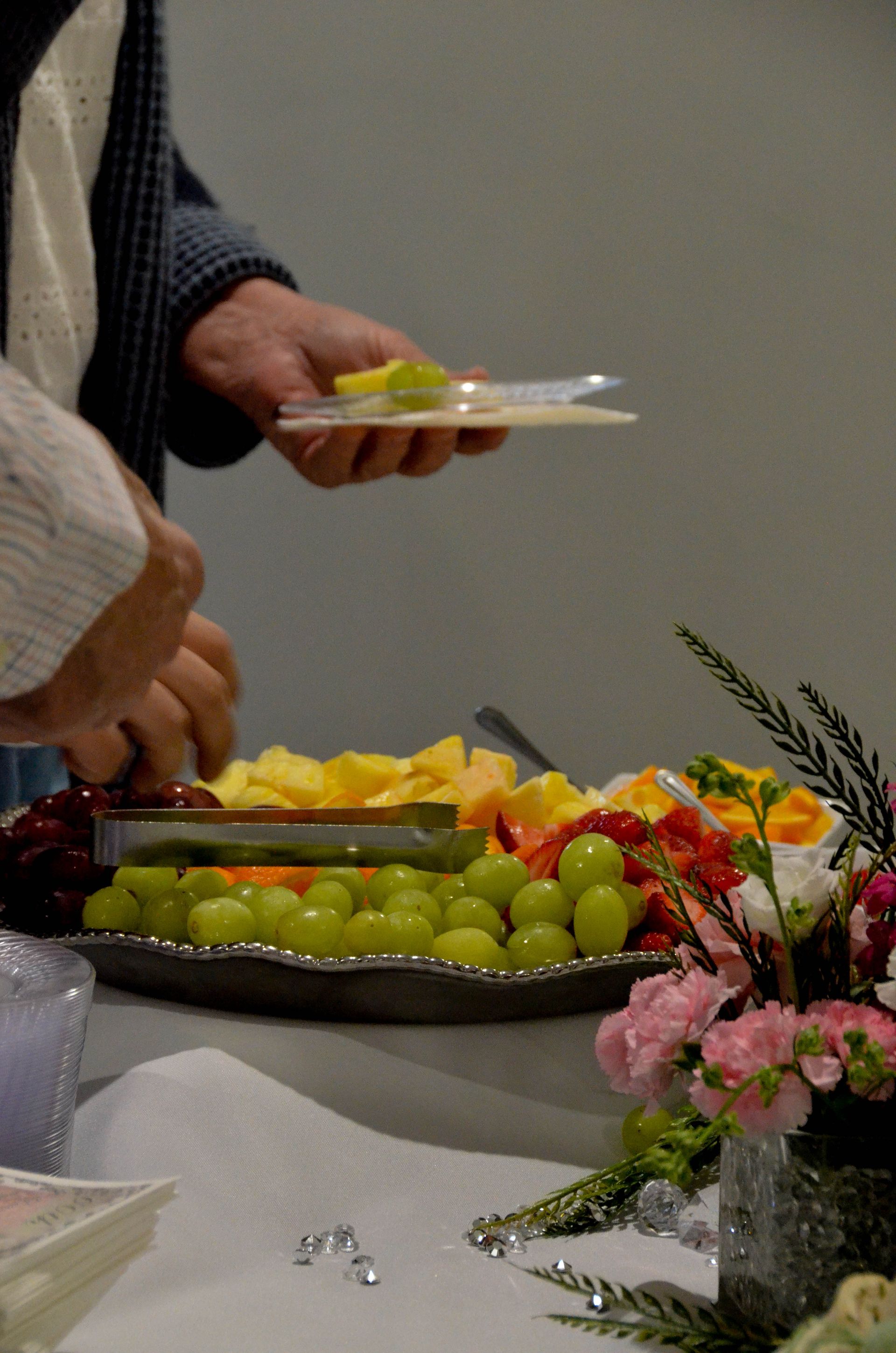 A person is serving a plate of fruit to another person.