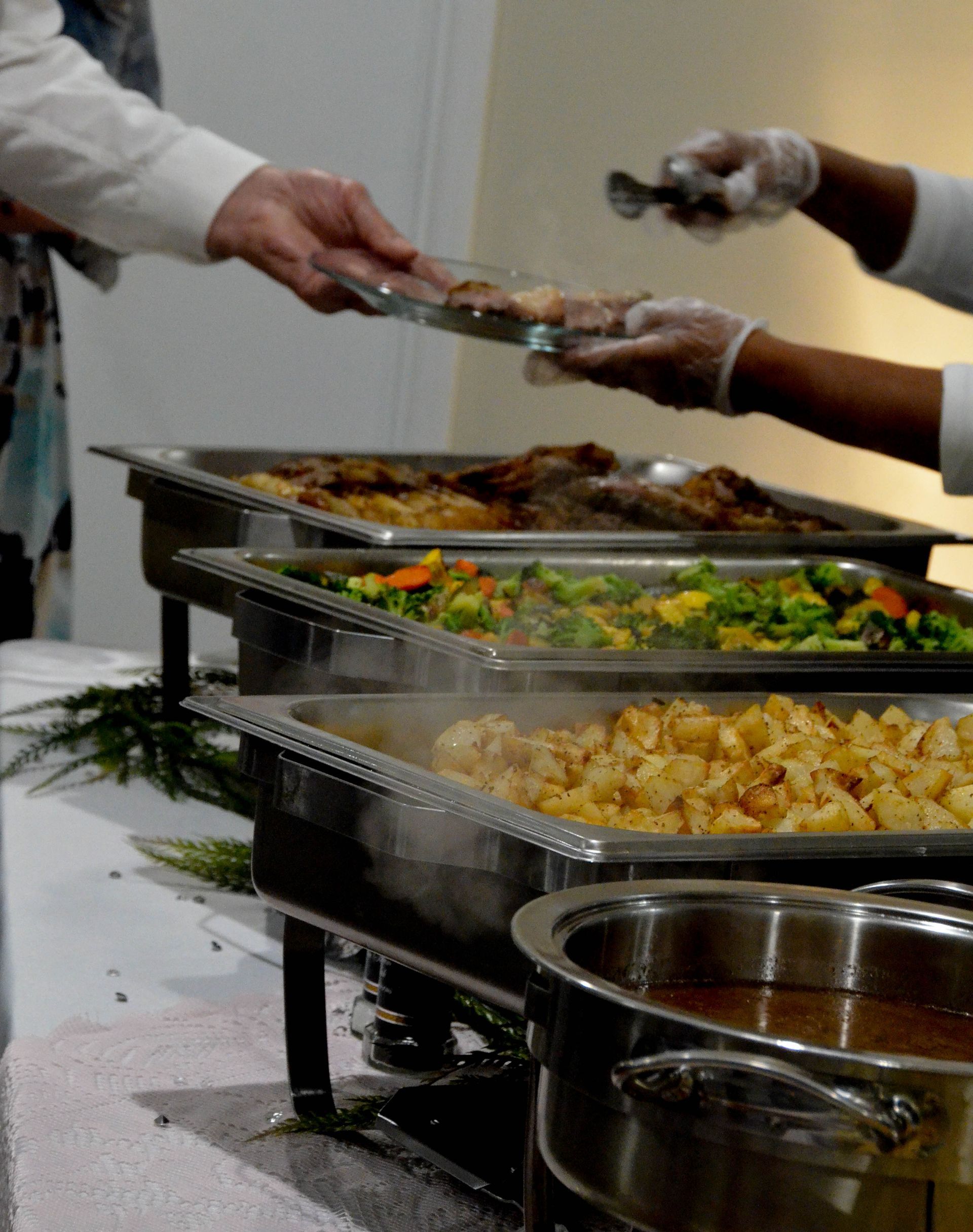A person is taking a tray of food from a buffet line