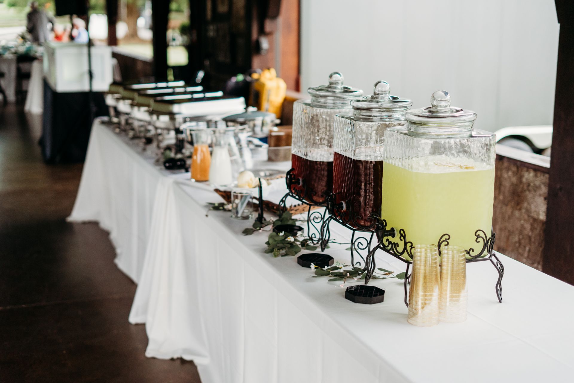 A long table with a row of drink dispensers on it.
