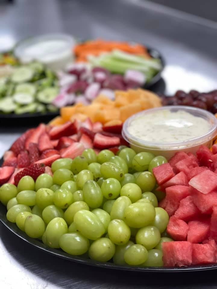 A black plate topped with grapes , watermelon , strawberries and other fruit.