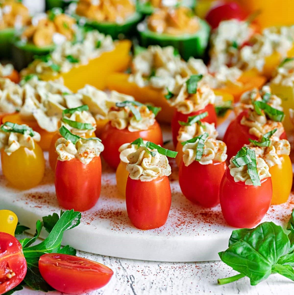 A white plate topped with stuffed tomatoes and other vegetables.