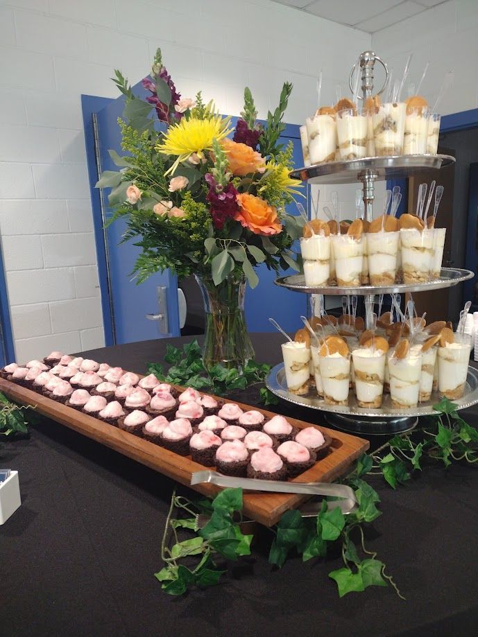 A table topped with a variety of desserts and a vase of flowers.