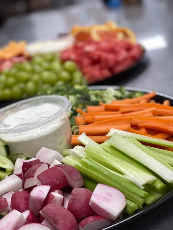 A tray of vegetables with ranch dressing on a table.