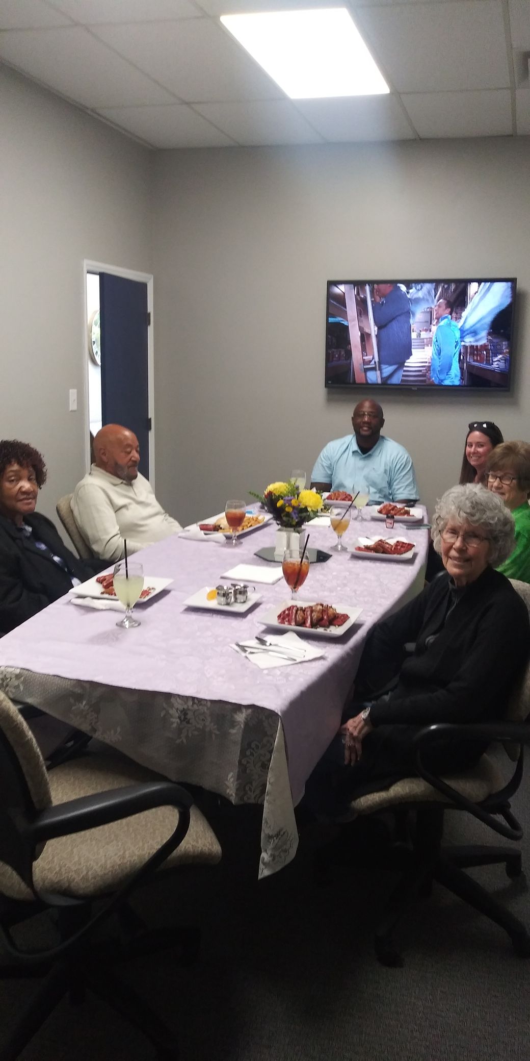 A group of people are sitting around a long table with plates of food.