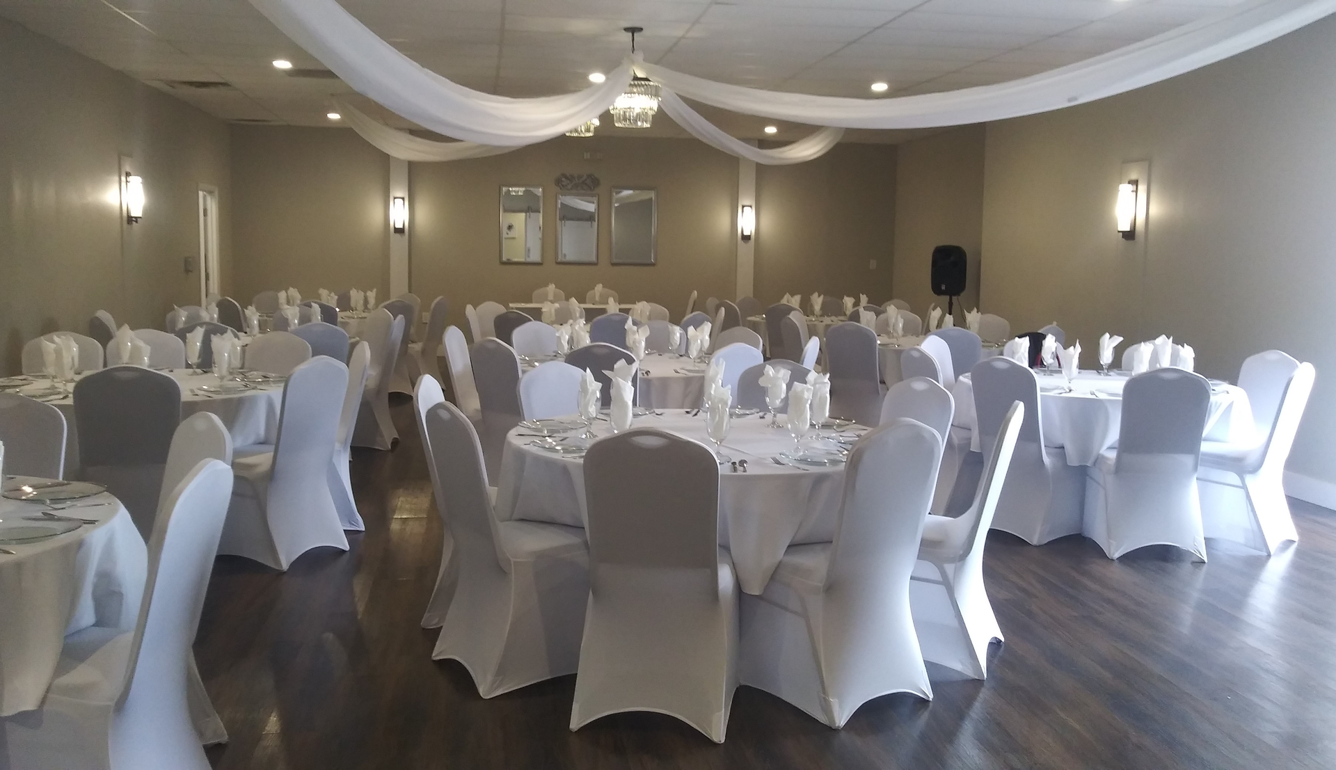 A large room with tables and chairs set up for a wedding reception.