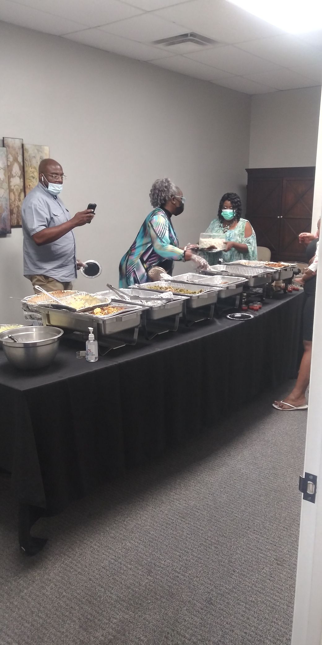 A group of people are standing around a long table filled with food.