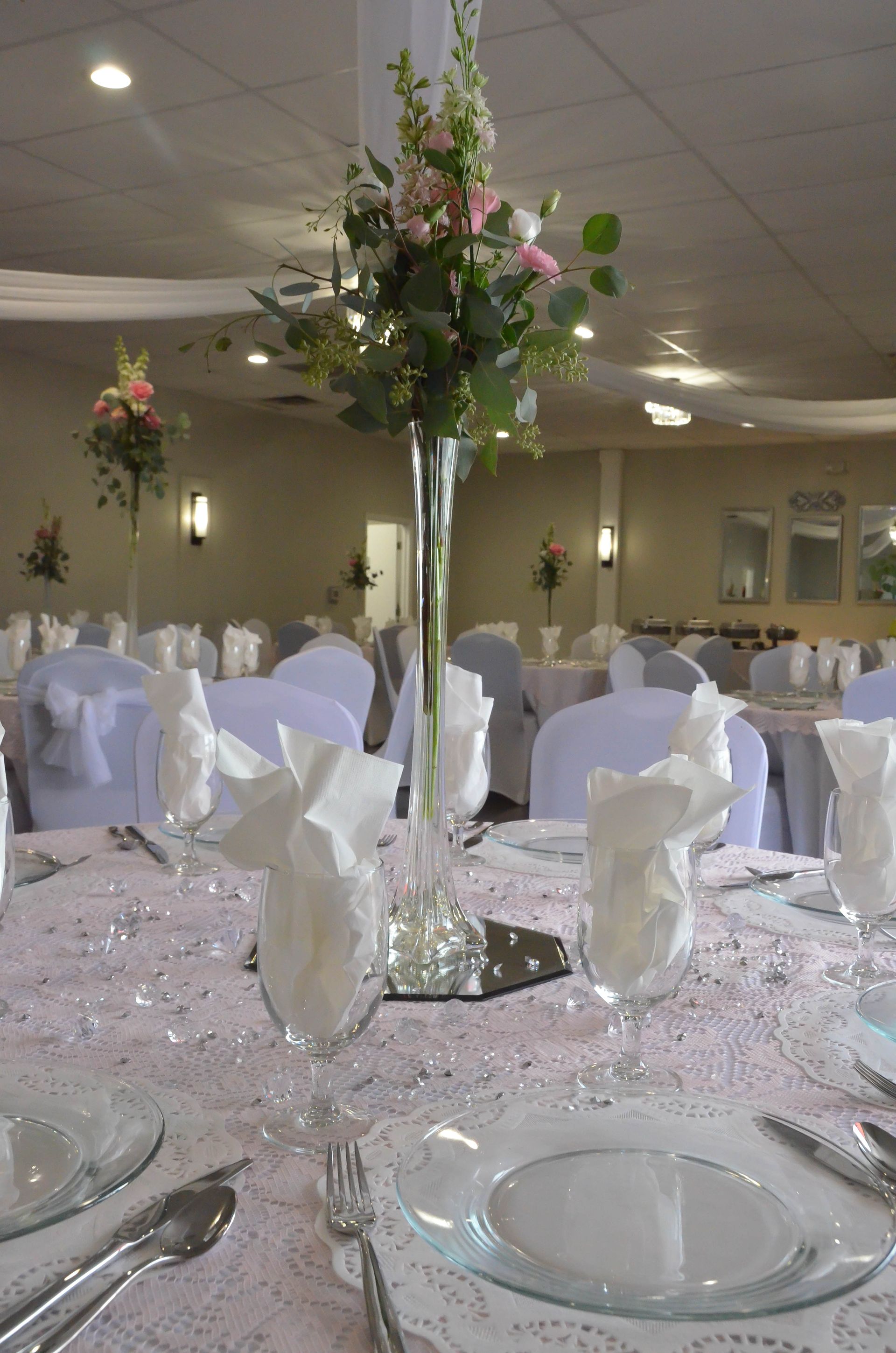 A table set for a wedding reception with a vase of flowers on it