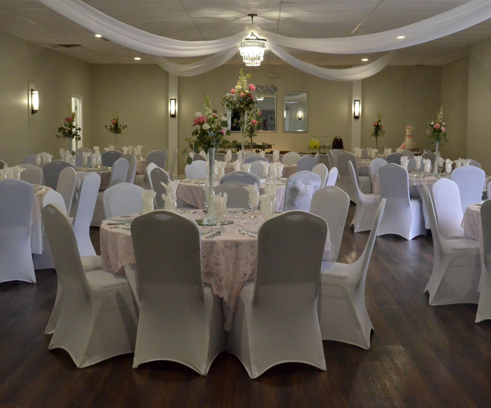 A large room with tables and chairs set up for a wedding reception