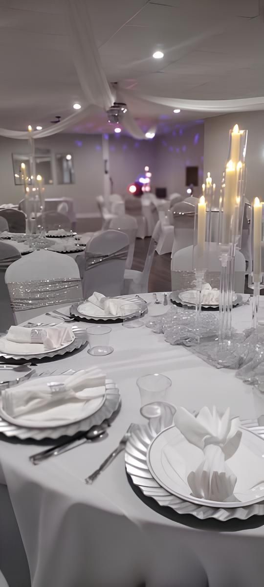 A table set for a wedding reception with plates , silverware , and candles.