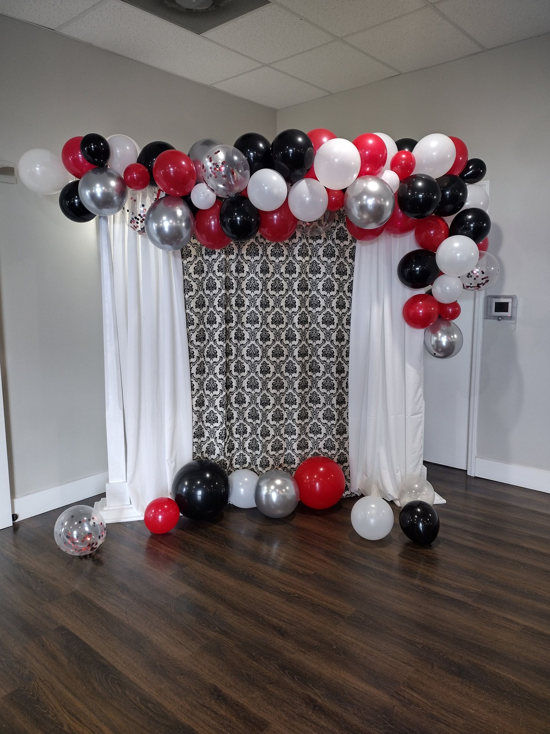 A room decorated with red , white and silver balloons
