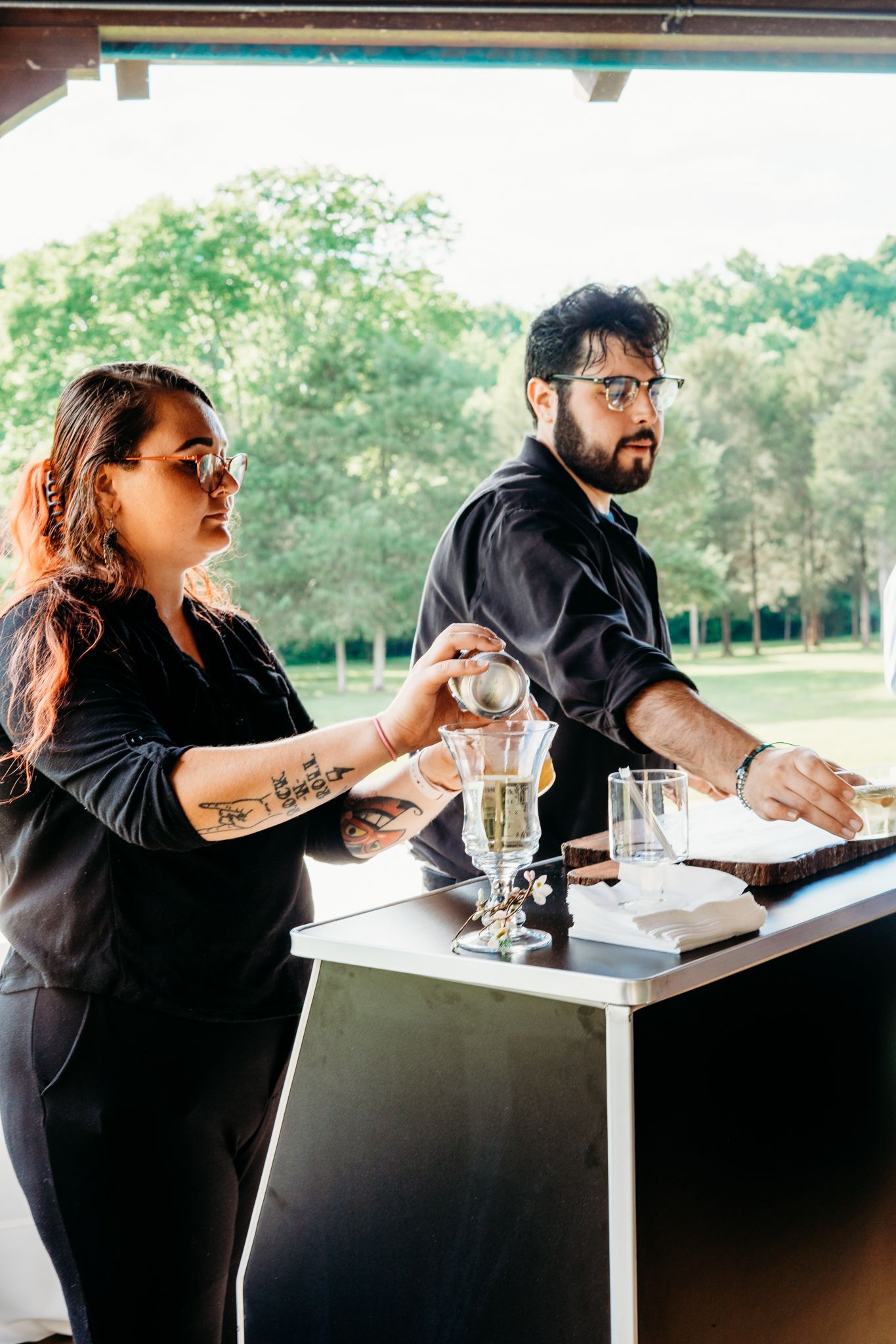 A man and a woman are standing at a bar preparing drinks.