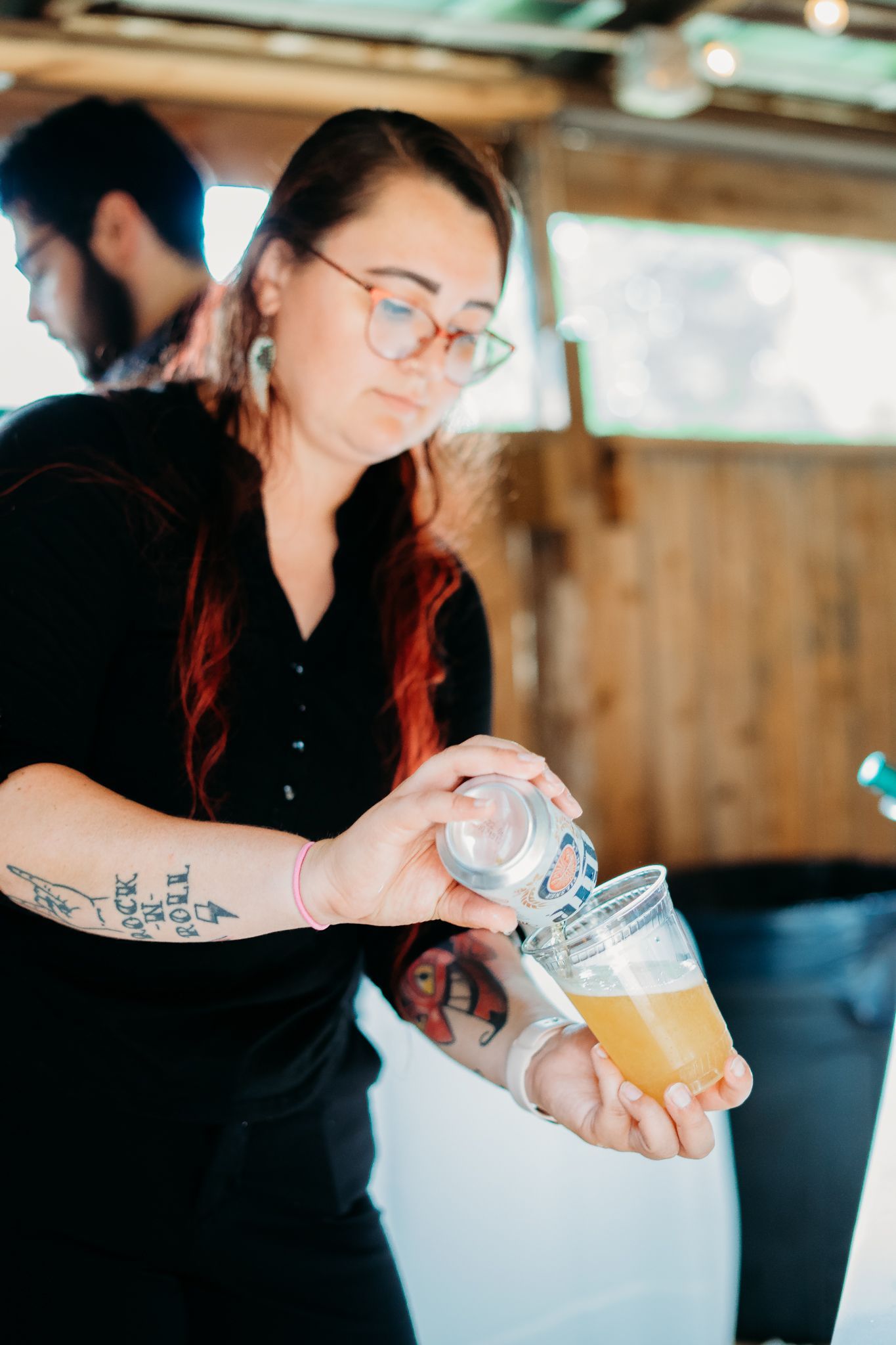 A woman is pouring a drink into a glass.