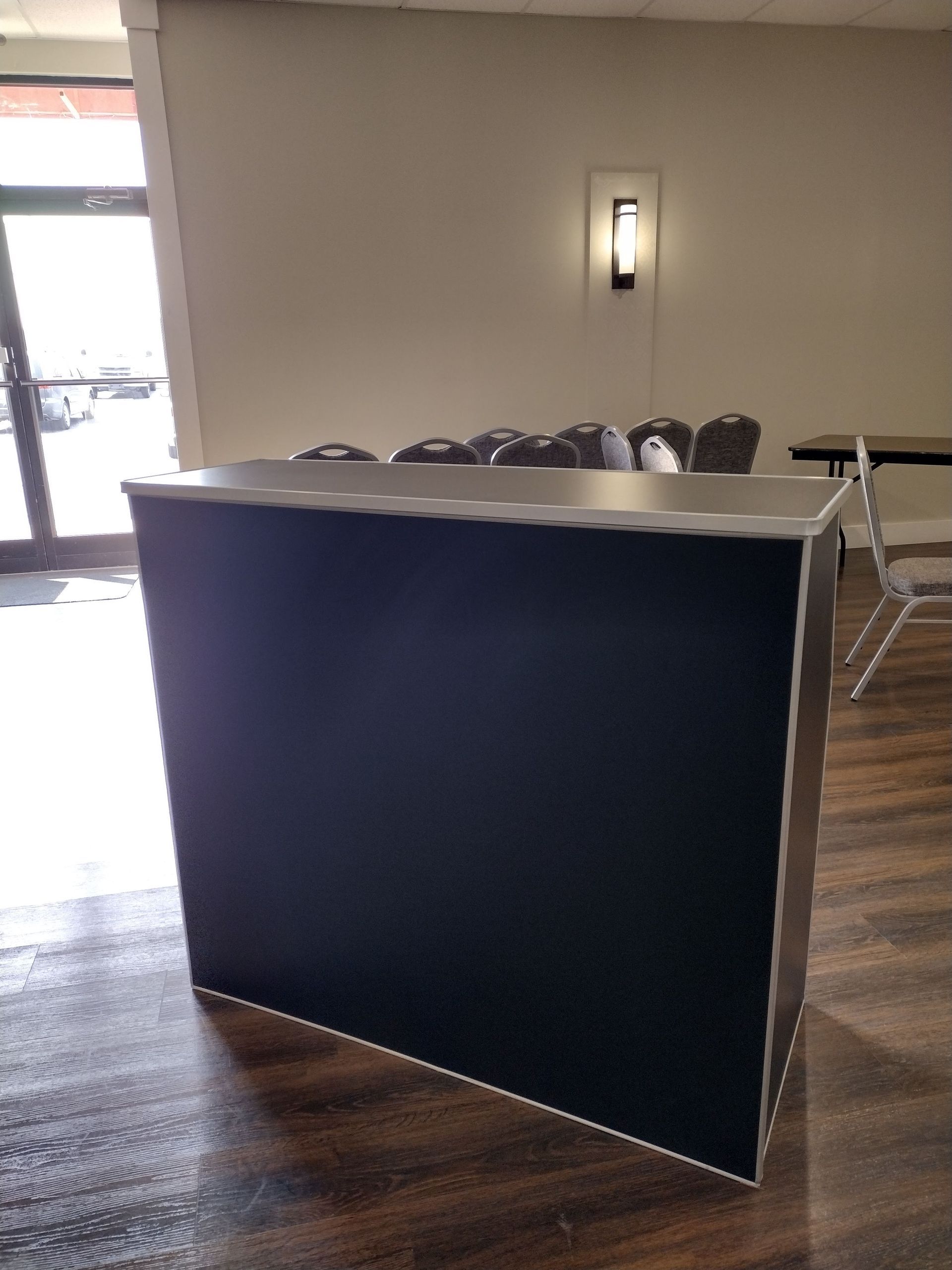A black bar is sitting in a room with tables and chairs.