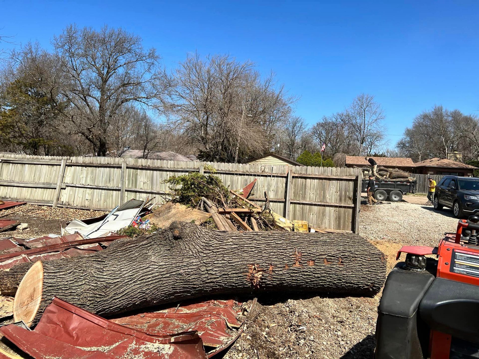 A large log is sitting in the middle of a yard next to a fence.